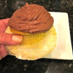 Holding a yellow cupcake with chocolate frosting